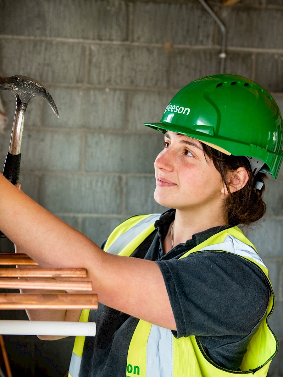 Worker smiling in front of site in PPE.