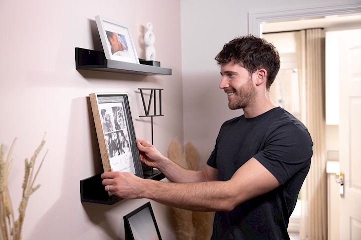 Young homeowner placing photos in his home