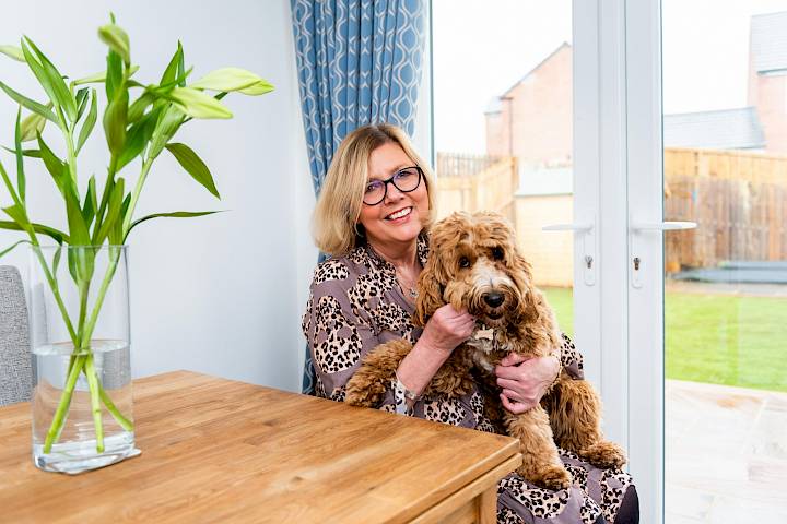 Happy woman sat with dog in new home.